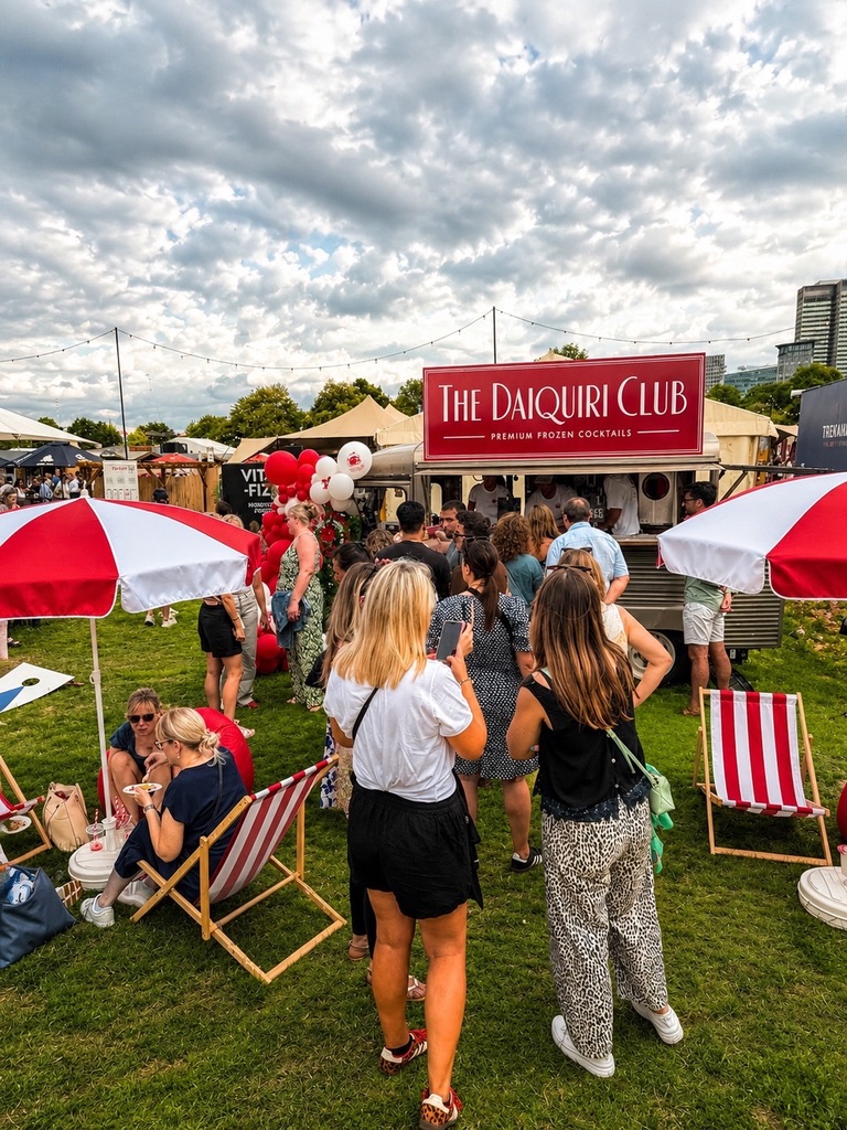 Crowd gathered at The Daiquiri Club van with striped deckchairs