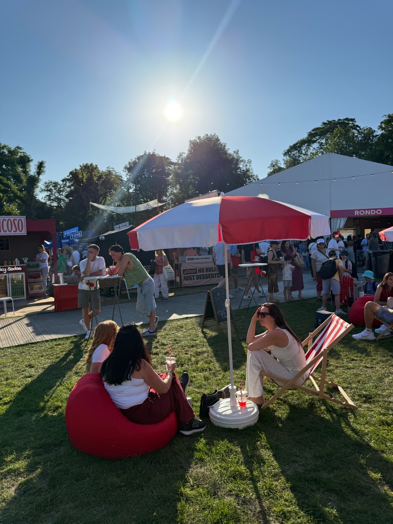 Guests relaxing on red bean bags and striped deckchairs in the festival sun