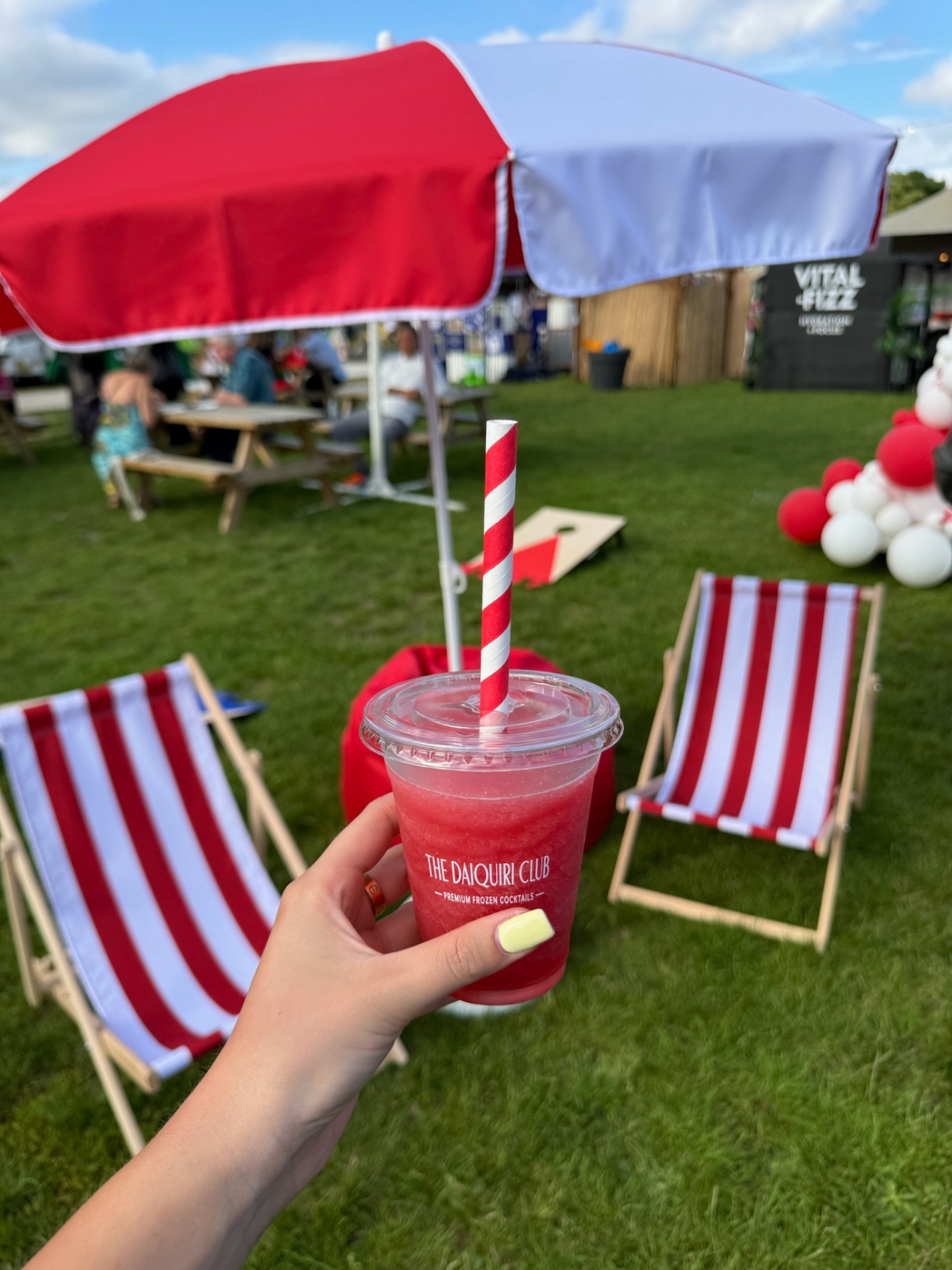 Frozen daiquiri held under a red and white umbrella with striped deckchairs