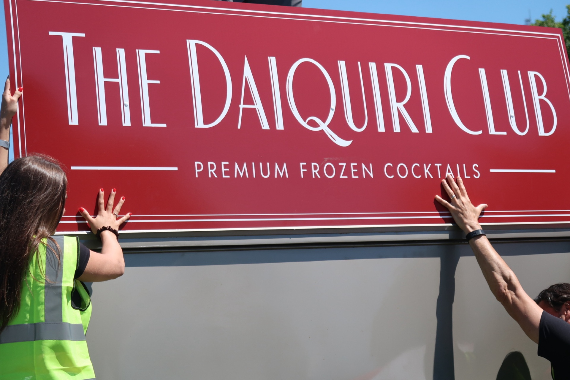 Team lifting the red Daiquiri Club sign into place at setup
