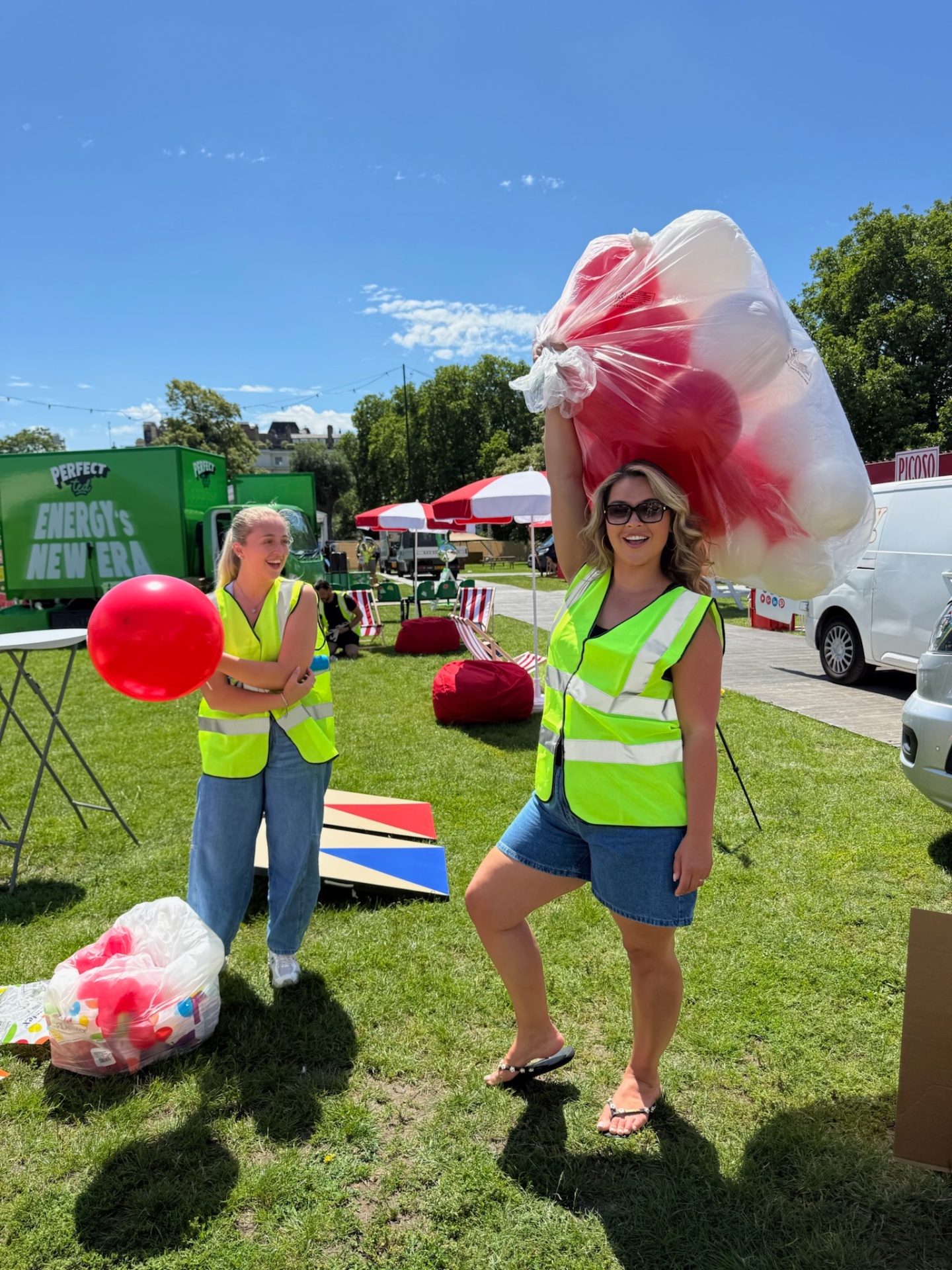Team members in hi-vis carrying bags of red and white balloons at set up