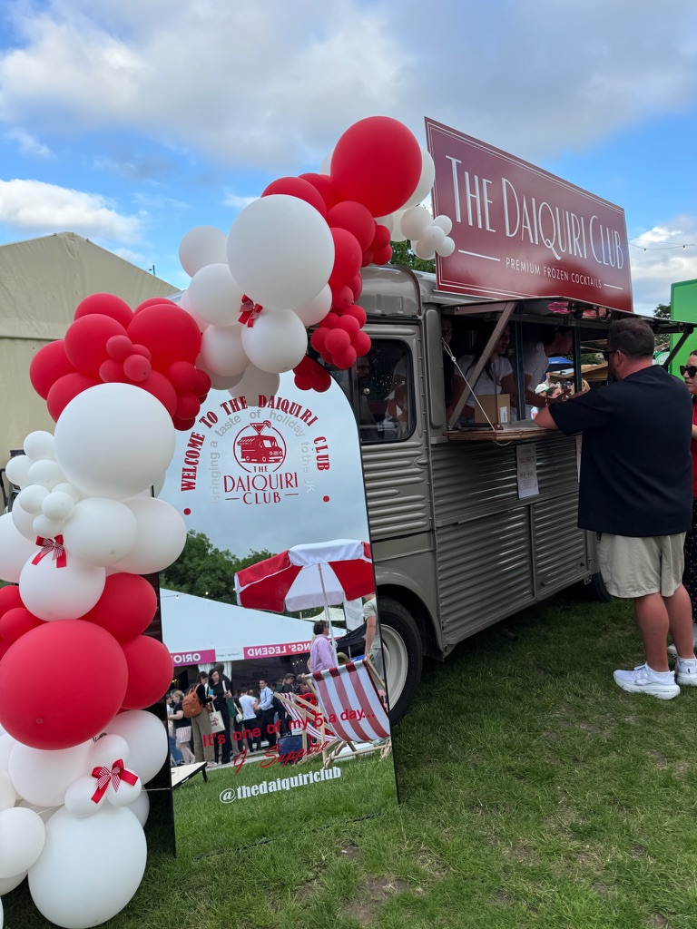 Red and white balloon arch beside the Daiquiri Club van